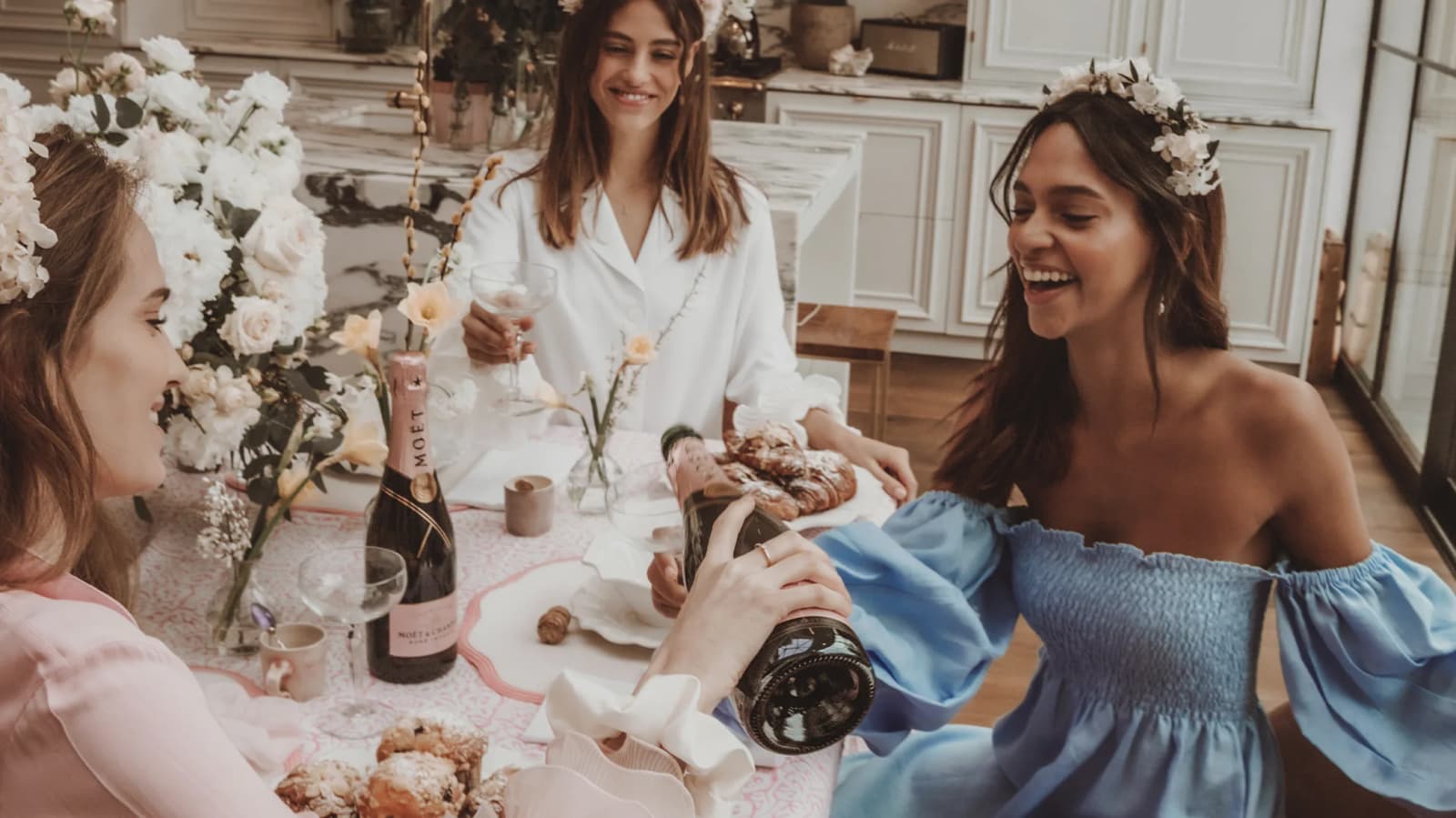 Stylish bride-to-be with her friends enjoy hen do brunch with champagne and pastry.
