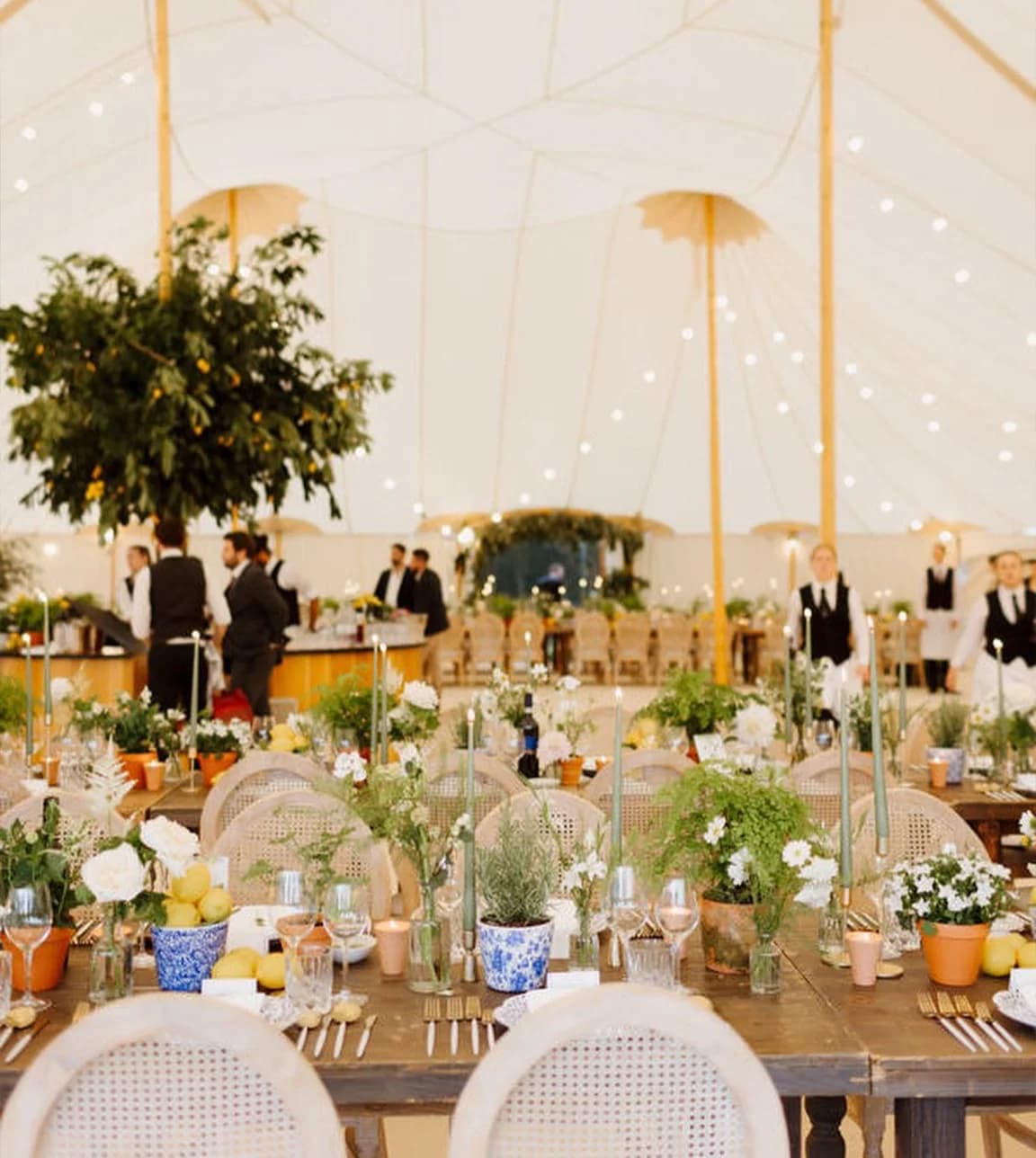 Table décor and catering staff inside a wedding marquee