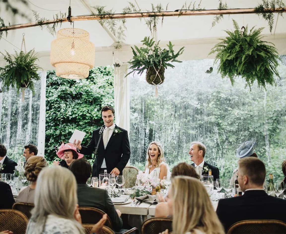 Wedding speeches at marquee during rain