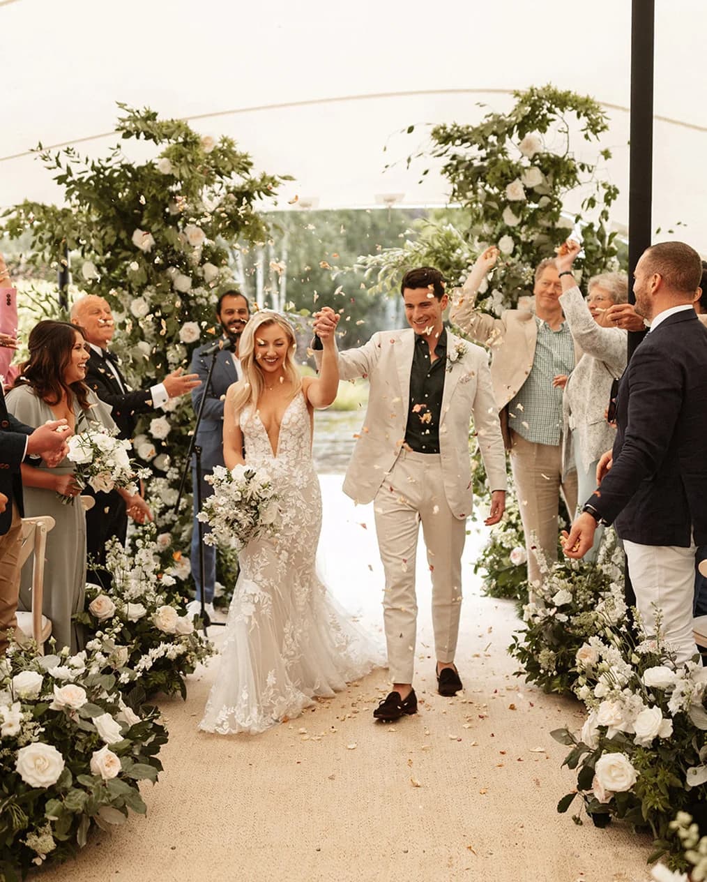 Bride and groom walk into confetti during their marquee wedding ceremony