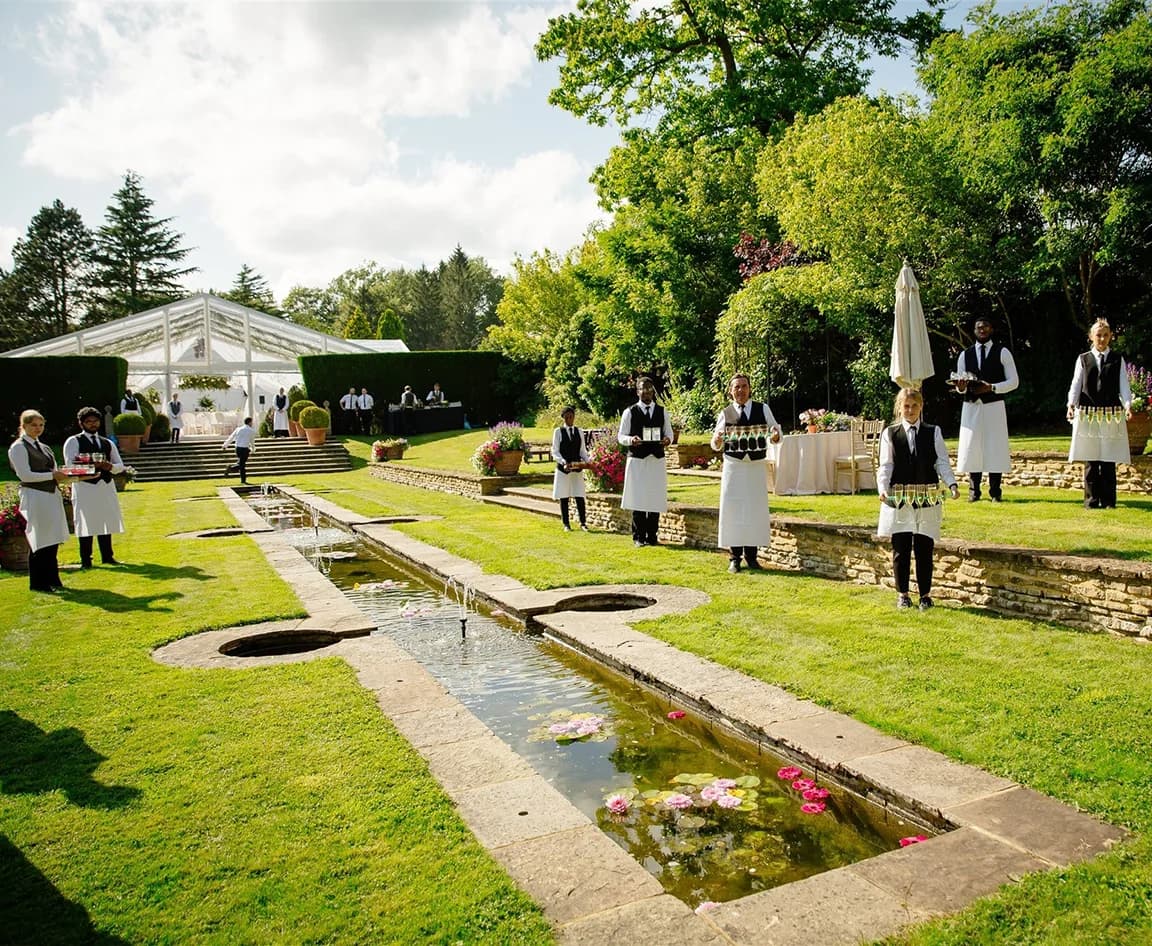 Catering staff waits outside marquee at lush garden venue