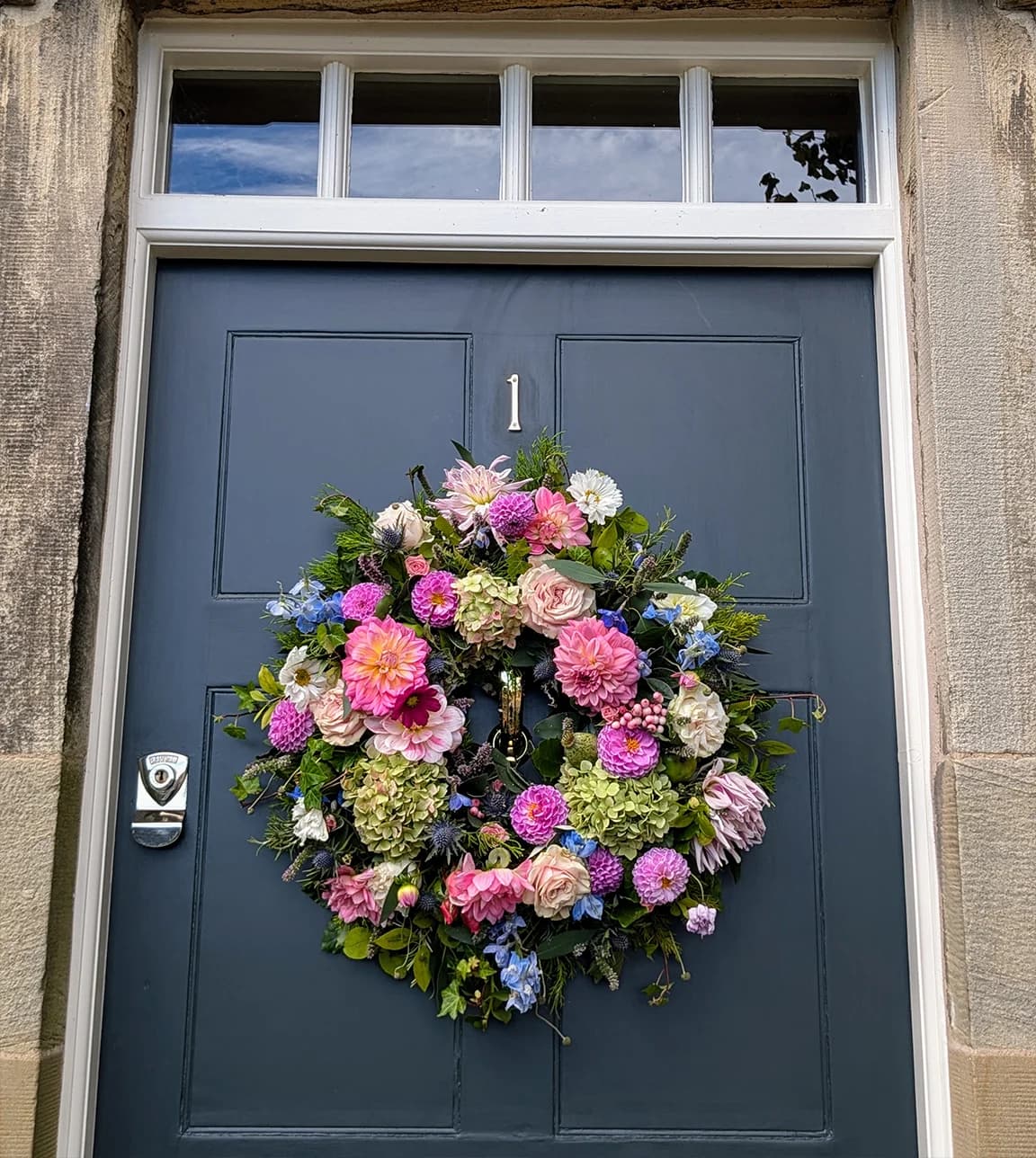 Colourful wedding wreath hung on the blue door