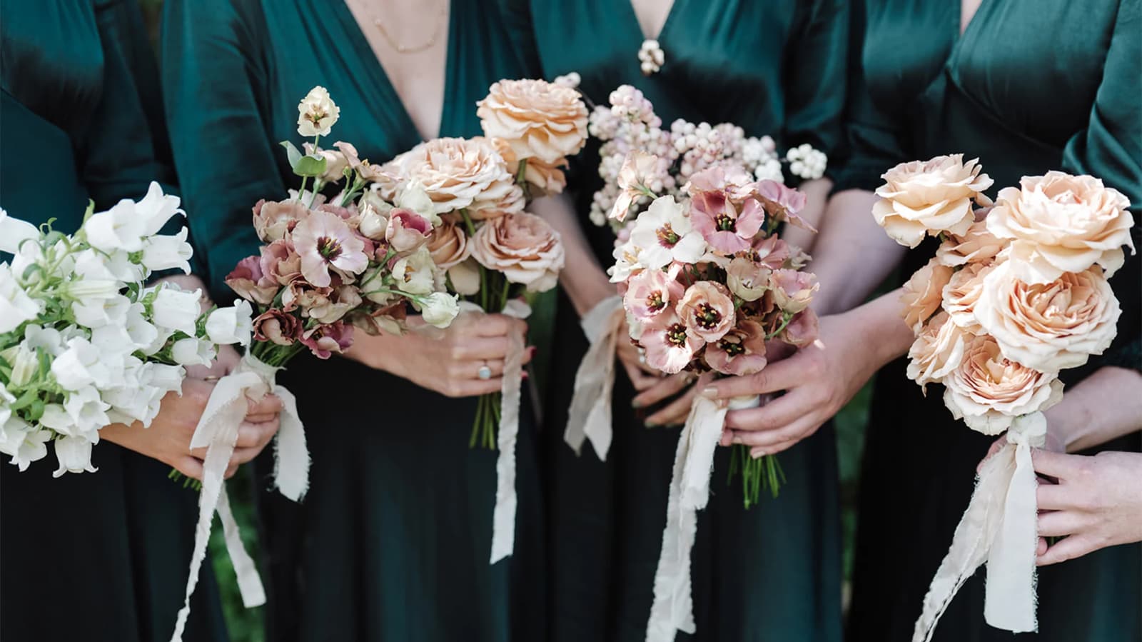 Brides in emerald green dresses hold different autumnal bridesmaids bouquets.