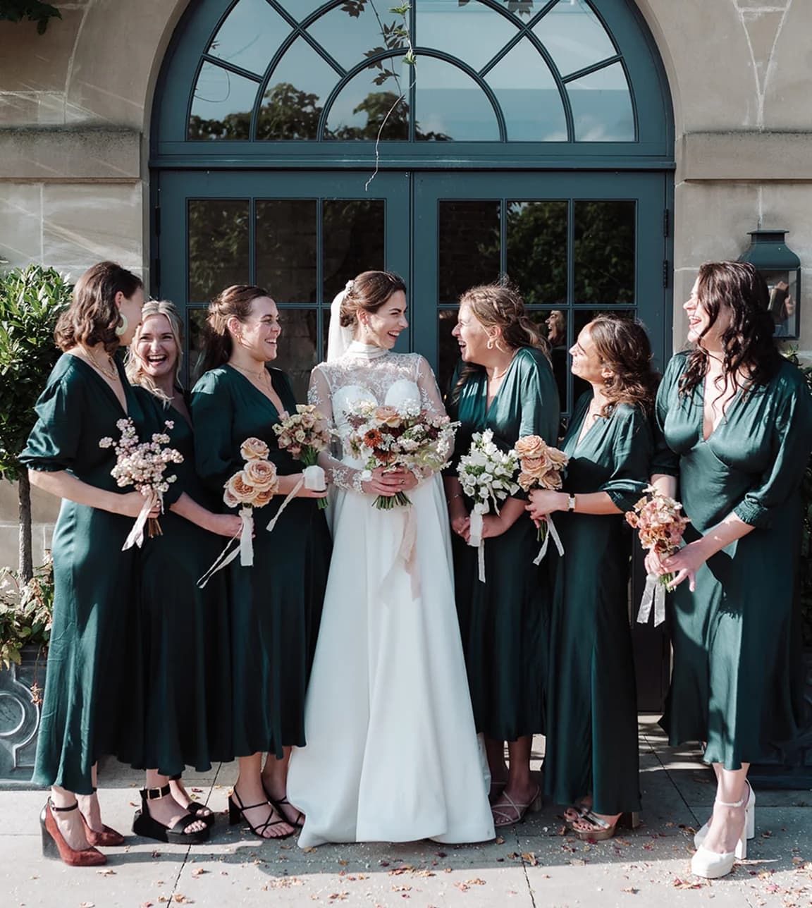 Bride pose with her bridesmaids wearing deep green bridesmaids dresses