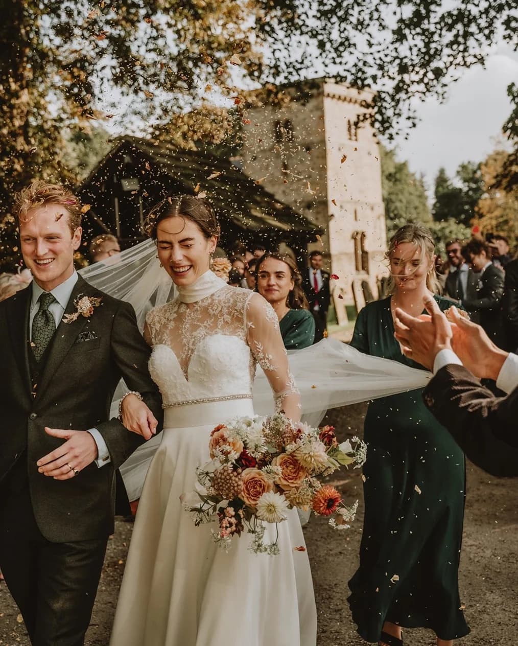 Bride and groom leave the church while guests throw confetti