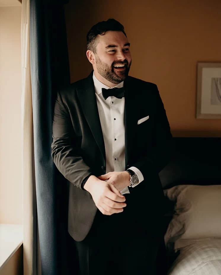 Groom is getting ready, wearing black tie tux, neck tie and white shirt