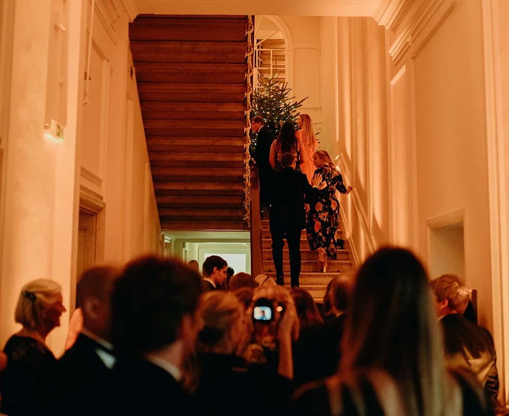 Wedding guests walk up the stairs to attend winter wedding at The Belgravia