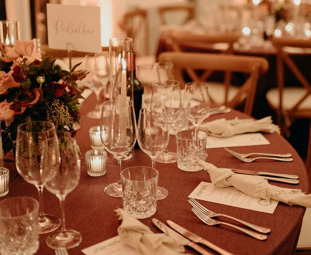 Winter wedding table set with glasseware on deep red tablecloths