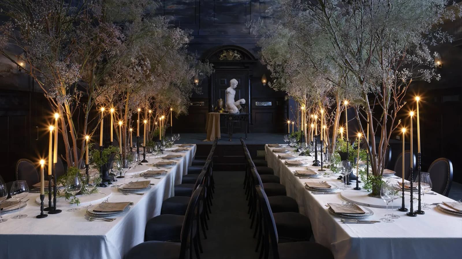 Elegant wedding reception at NoMad Hotel London with candlelit banquet tables, trees décor, and a dramatic historic dining room