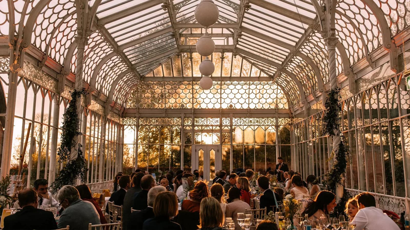 Wedding reception at Horniman House & Gardens London in a glass conservatory with sunset light and guests dining