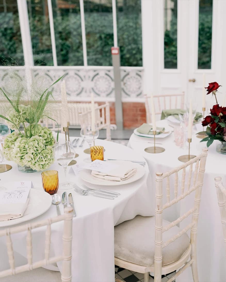 Wedding reception table at Horniman House & Gardens London with elegant place settings, floral centrepieces, and glass conservatory backdrop
