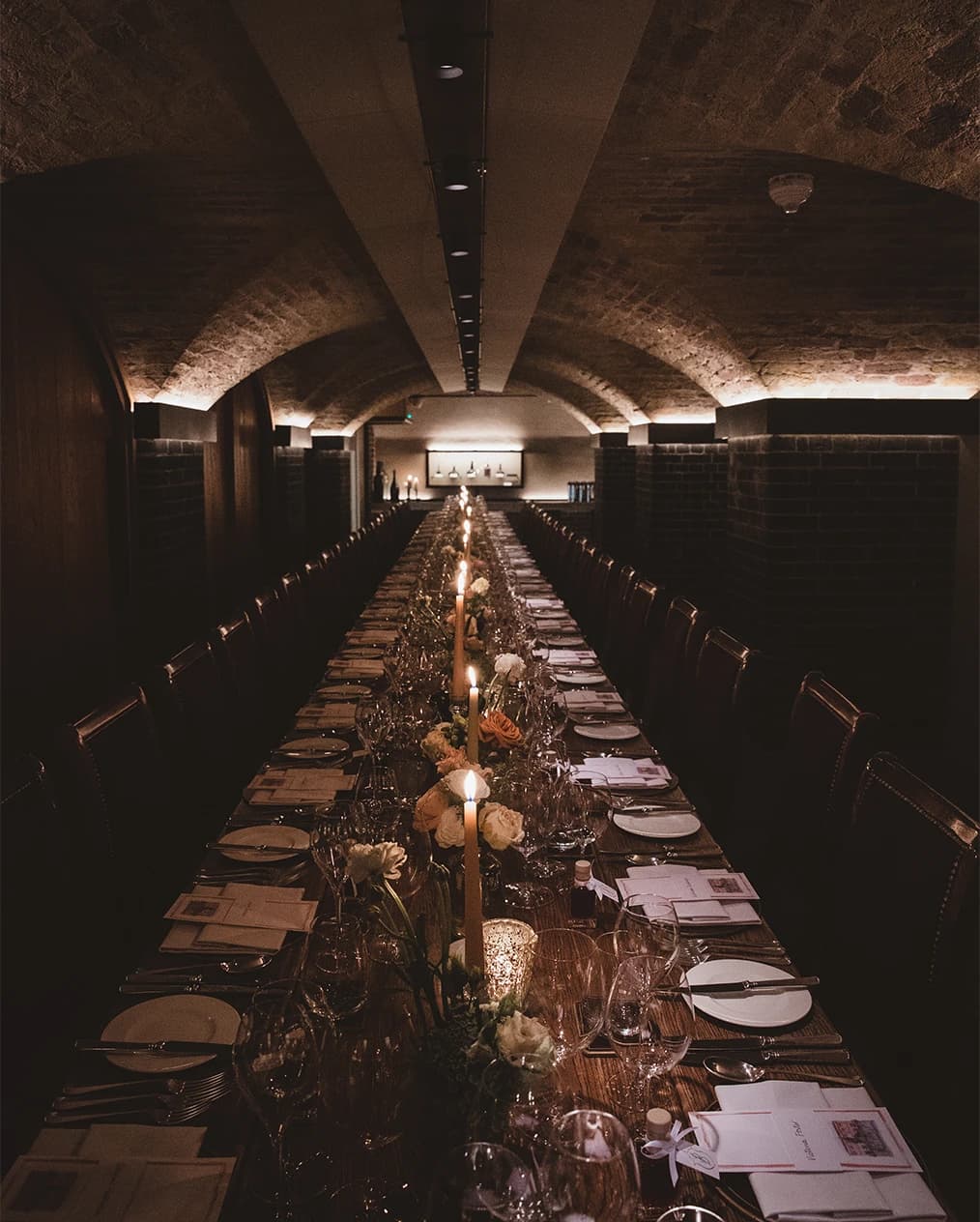 Wedding reception dinner at Berry Bros. & Rudd London with long table, candlelight, and vaulted wine cellar