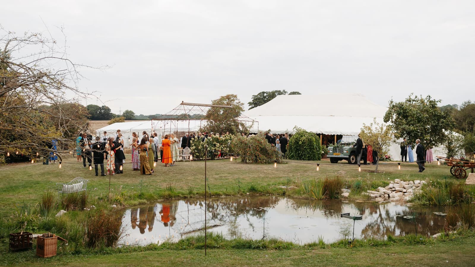 Guests gathering beside a lakeside marquee at a luxury countryside wedding venue, enjoying an outdoor wedding celebration.