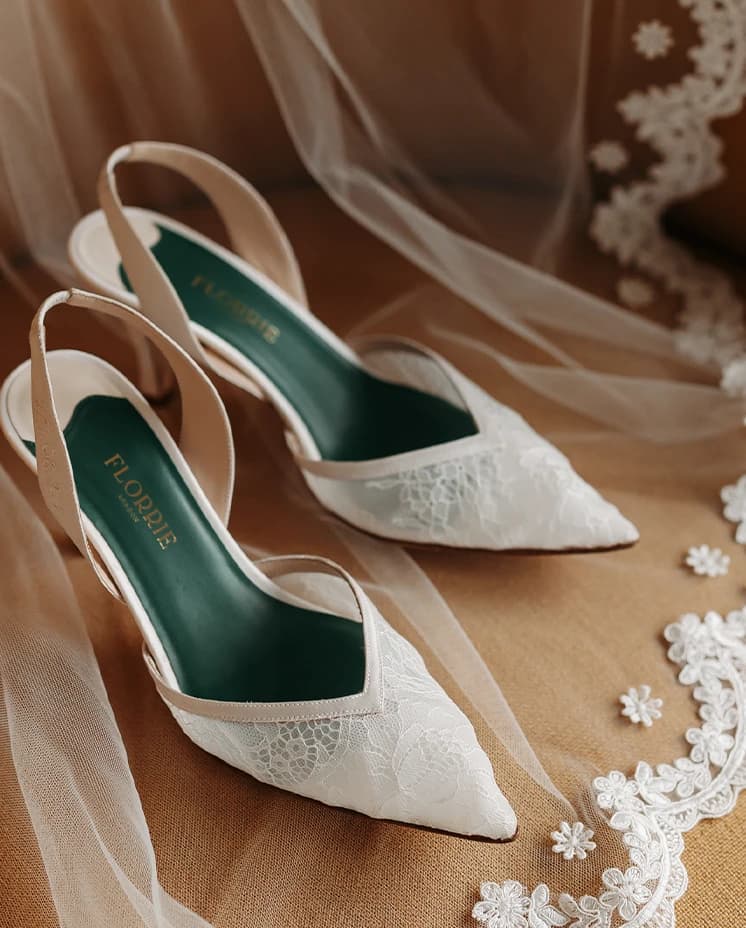 Custom lace bridal shoes by Florrie resting on a bridal veil