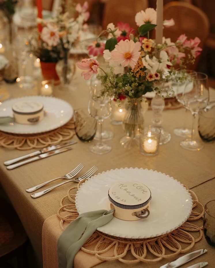 Luxury wedding tablescape with personalised tambourines, delicate floral centrepieces, candlelight and elegant place settings