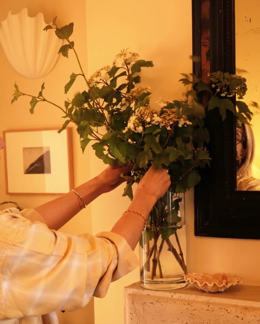 Lucy Williams is at home, arranging flowers in LSA International vase on her fireplace mantel