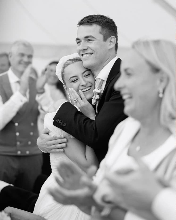 Bride and groom sharing an emotional embrace during heartfelt wedding speeches, captured in an elegant black and white portrait at their English countryside wedding reception.