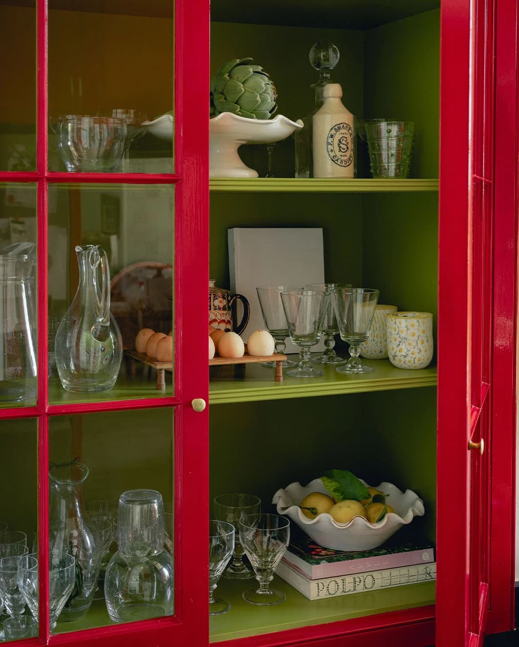 A green kitchen cabinet display with tableware and glassware wedding gifts