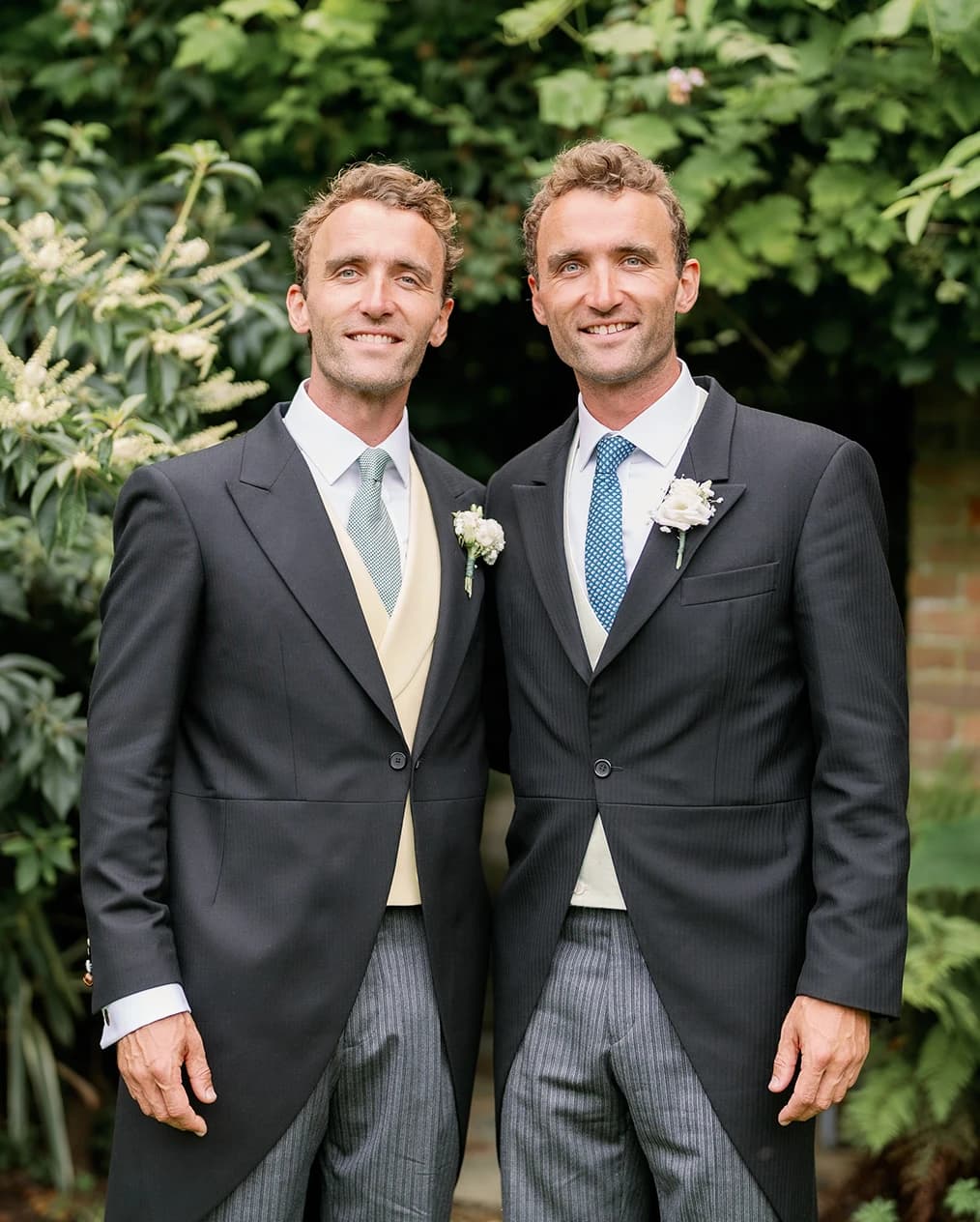 Groom with his twin brother, both wearing morning suits