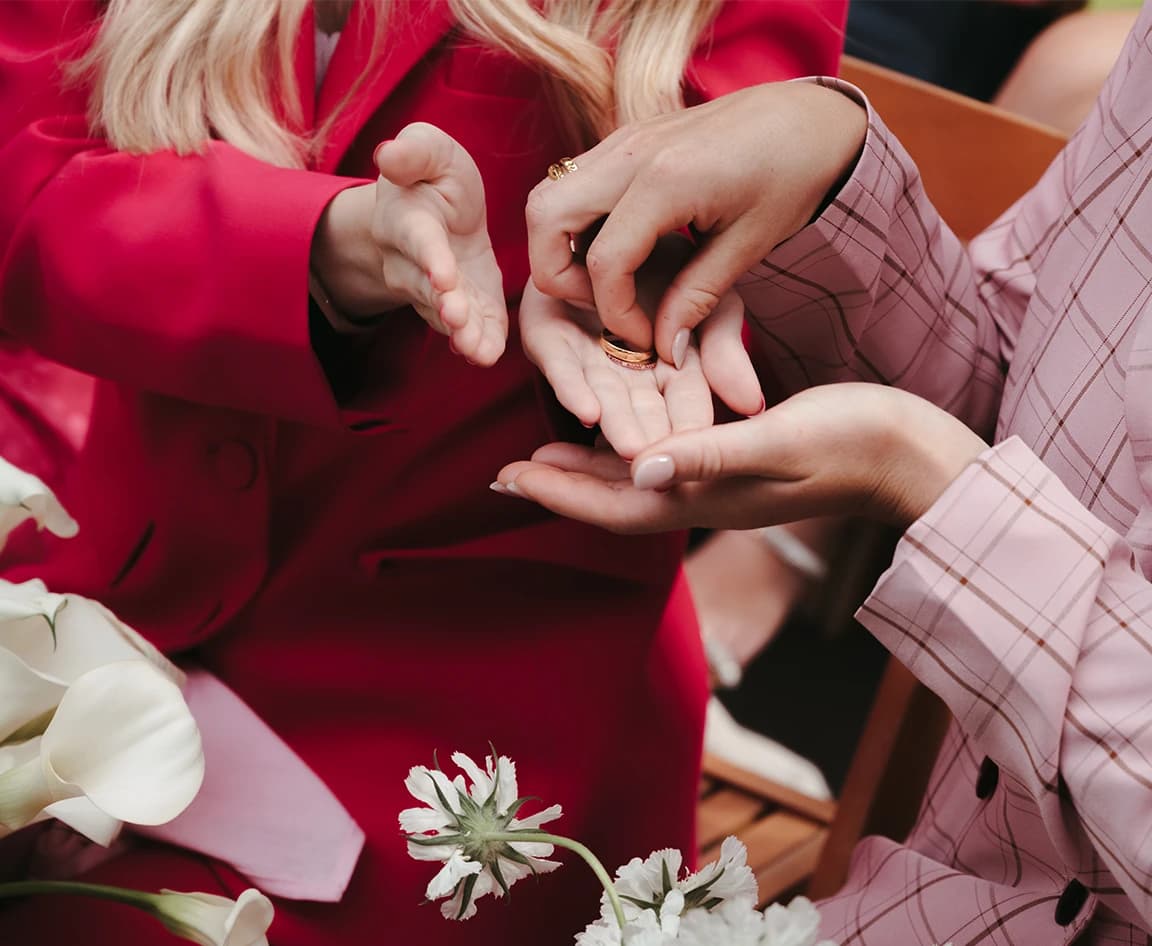 Guests in red and pink pass the wedding ring from hand to hand during a ring warming ceremony