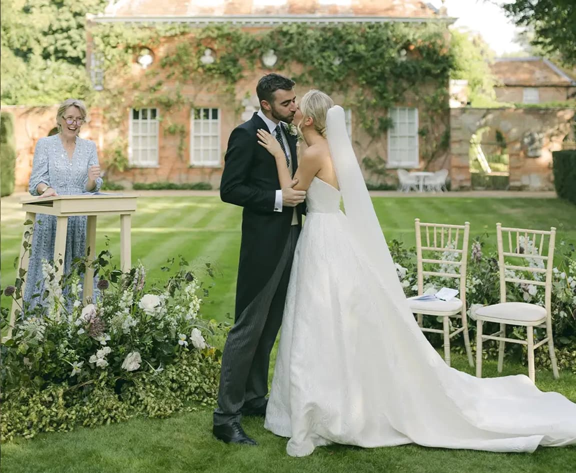 Bride and groom kissing during their wedding ceremony led by officiant