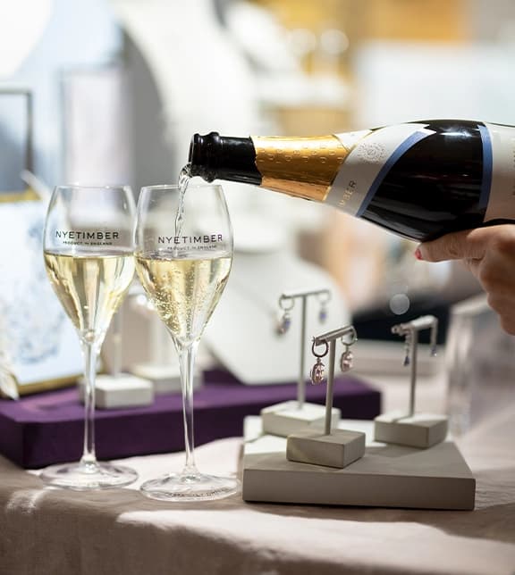 A showcase display of Kiki McDonough jewellery with glasses with Nyetimber sparkling wine