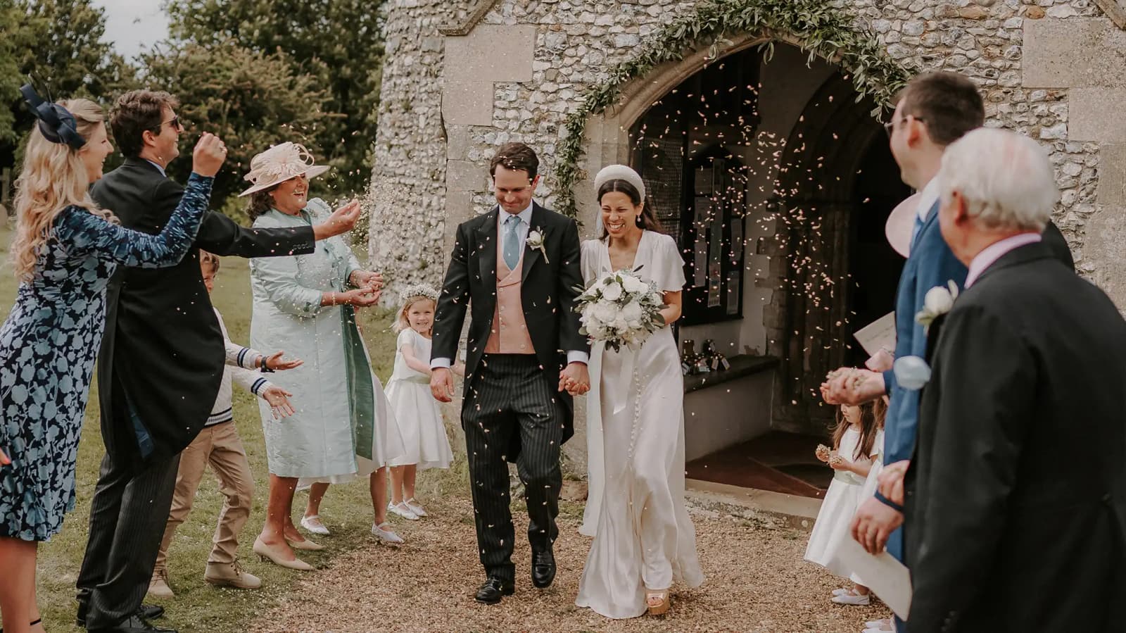 Wedding guests throws rice and cheer newlywed couple that leaves the church ceremony